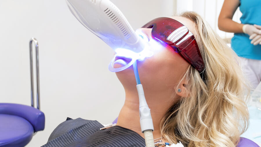 Closeup Portrait Of Young Woman Visiting Dentist Office For Teeth Whitening With Photopolymer
